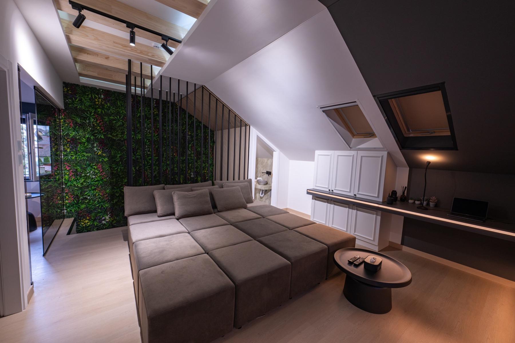 Modularna sofa razložena u ležaj, zeleni zid i radna zona sa laptopom
