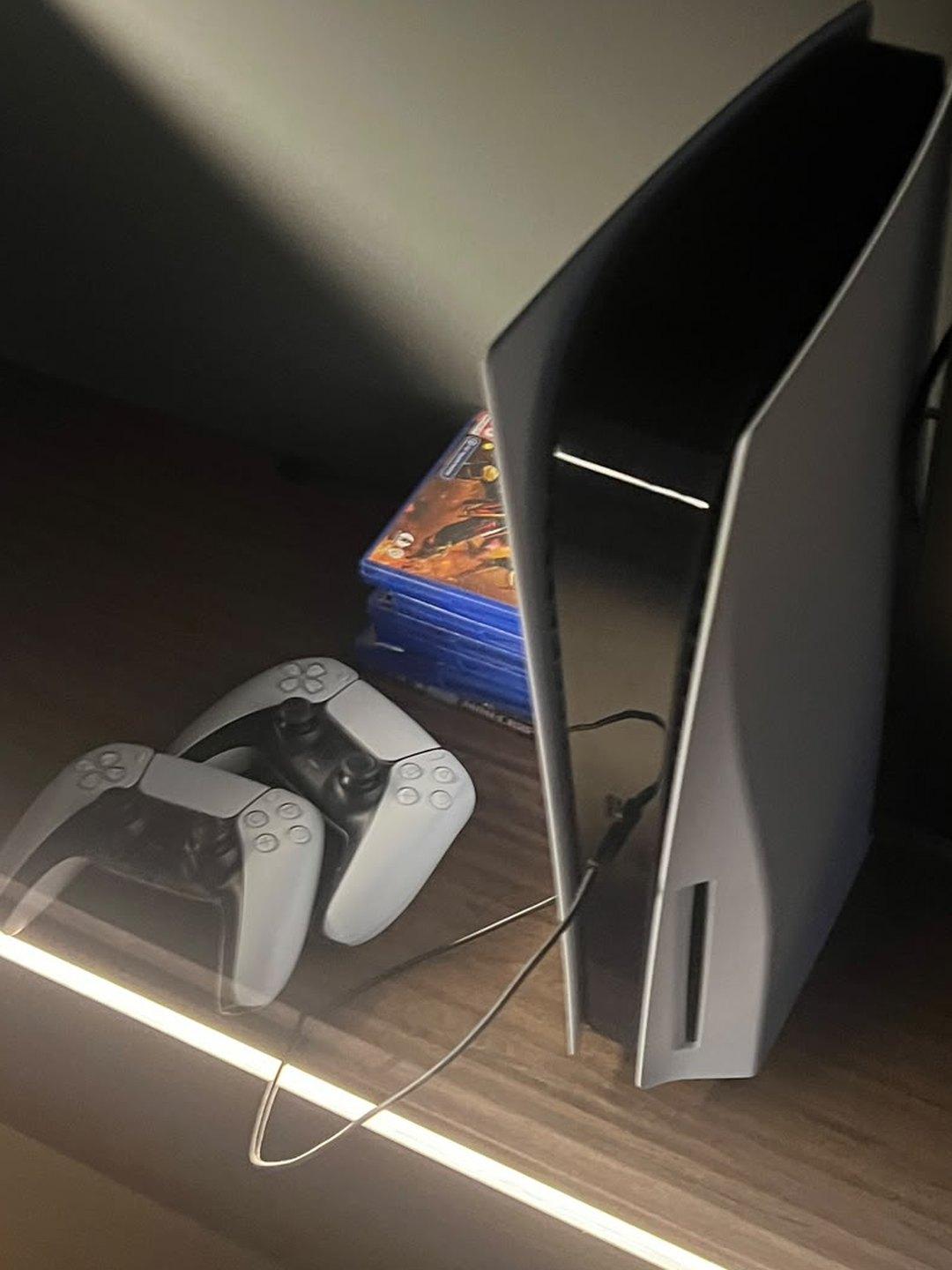 PlayStation 5 sa dva kontrolera i izborom igara u dnevnom boravku